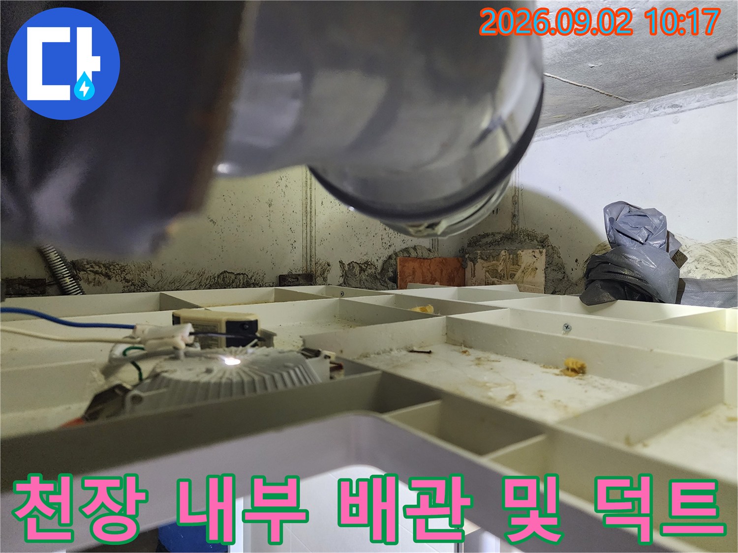 천장 점검구 안쪽의 환기 시설과 배관 고정 장치 모습입니다.
