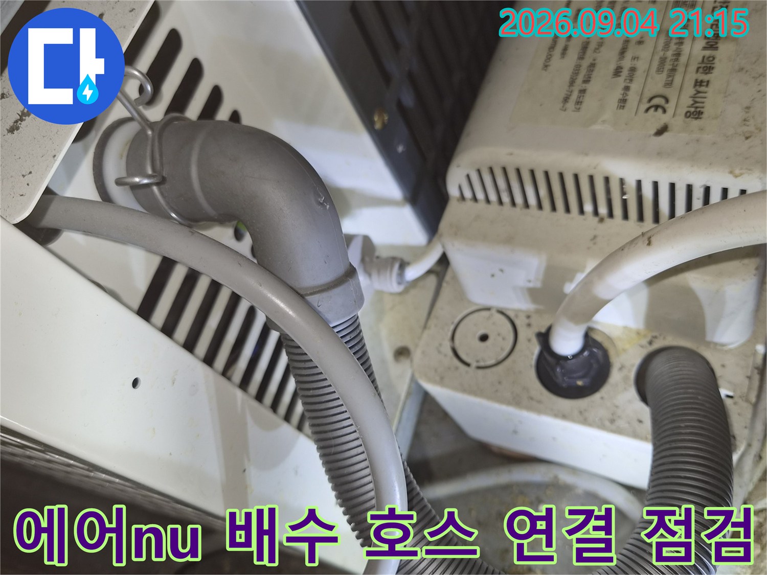 에어컨 드레인 배관과 굵은 주름관이 연결된 설비의 근접 촬영 사진입니다.