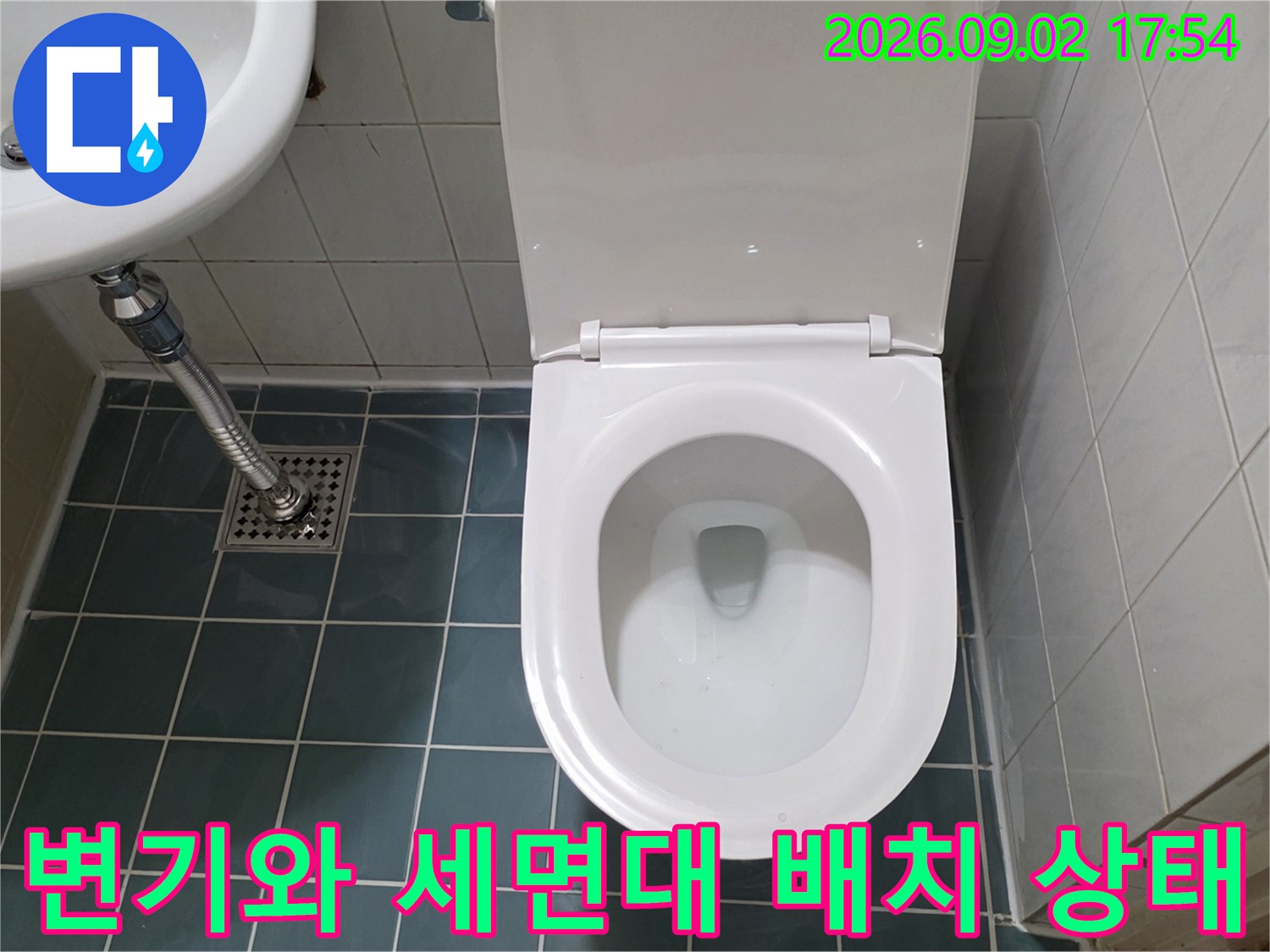 욕실 내 설치된 변기와 세면대의 전체적인 위치와 배관 연결부