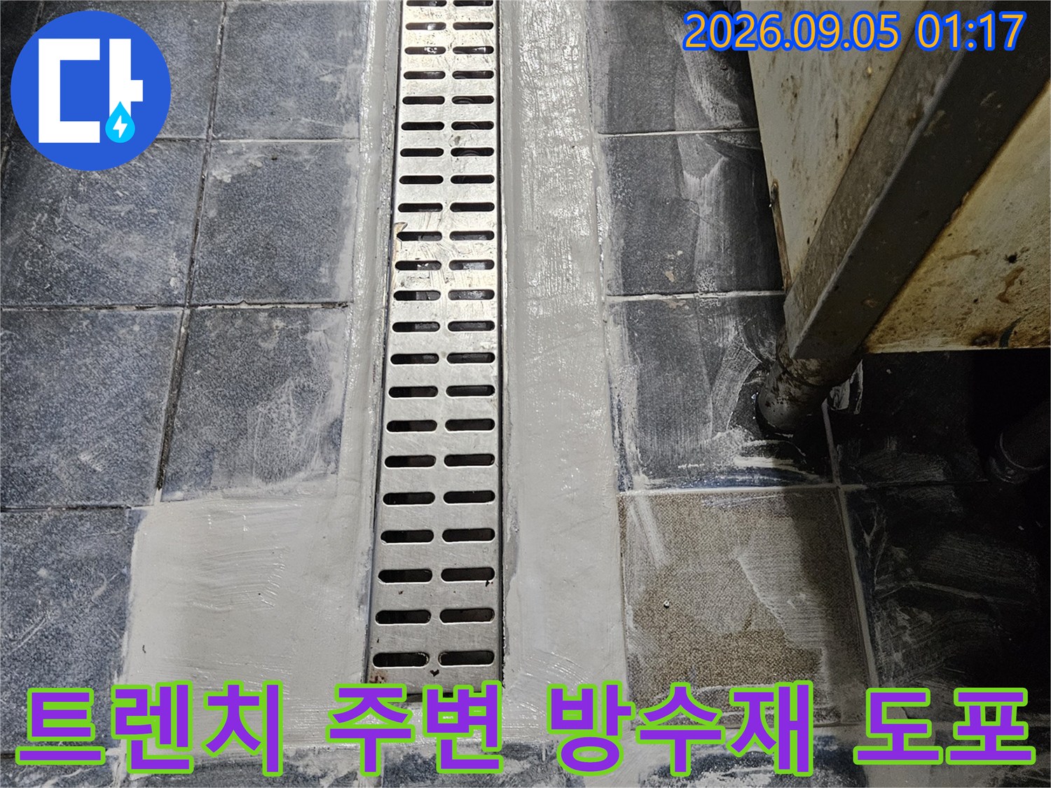 스테인리스 배수 트렌치 주변에 백시멘트로 마감된 타일 벽면