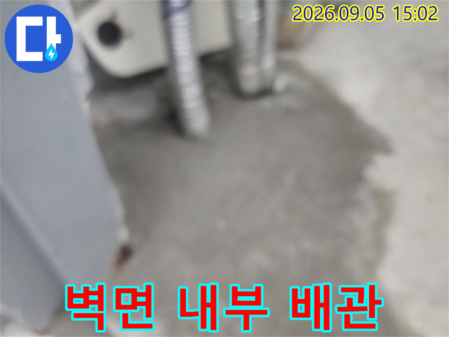 벽면 틈 사이로 보이는 은색 보온재를 입은 배관들