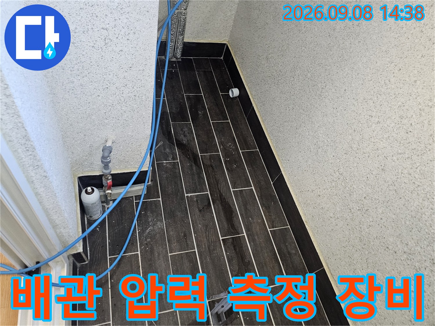 어두운 색 타일 벽면-배관 압력 검사를 위해 설치된 콤프레샤 호스와 게이지 연결 부위