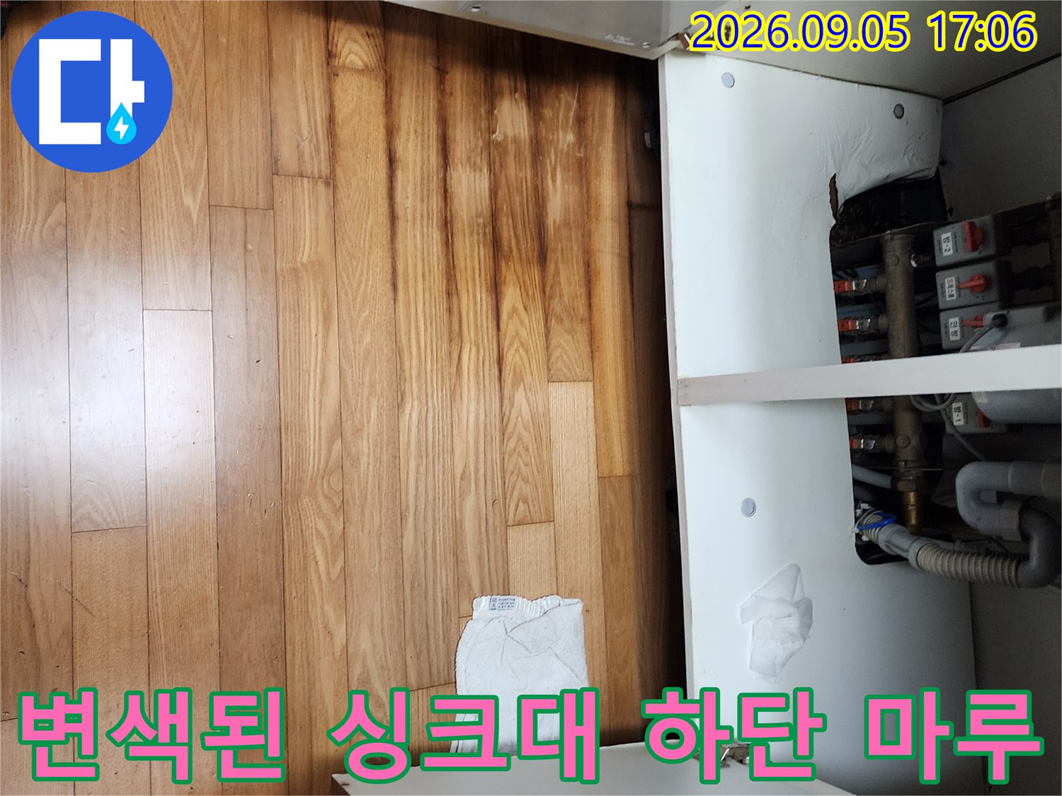 싱크대 아래쪽 배관 주변의 젖은 마루 바닥입니다.