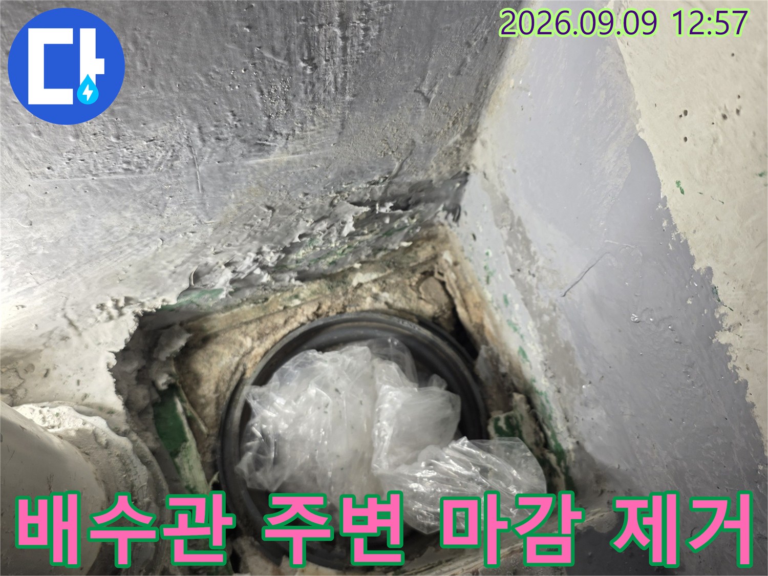 배수관 주변의 젖은 시멘트와 노출된 배관 연결부