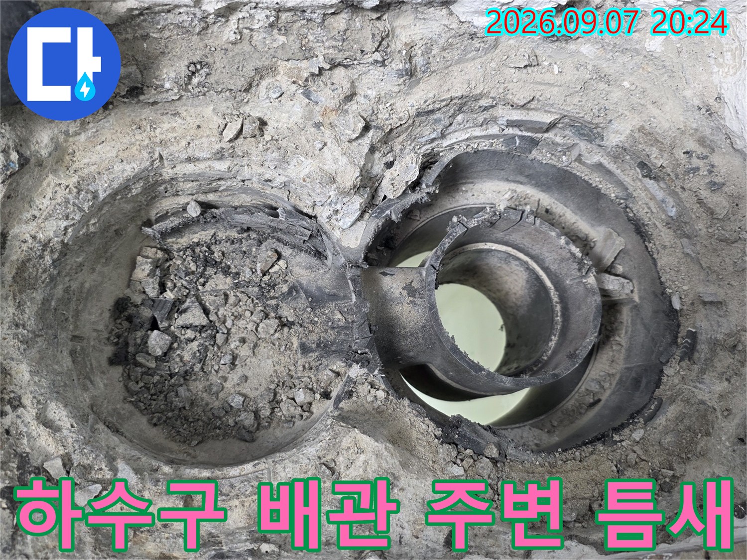 하수구 배관 사이의 벌어진 틈과 부식된 마감재를 보여주는 사진입니다.