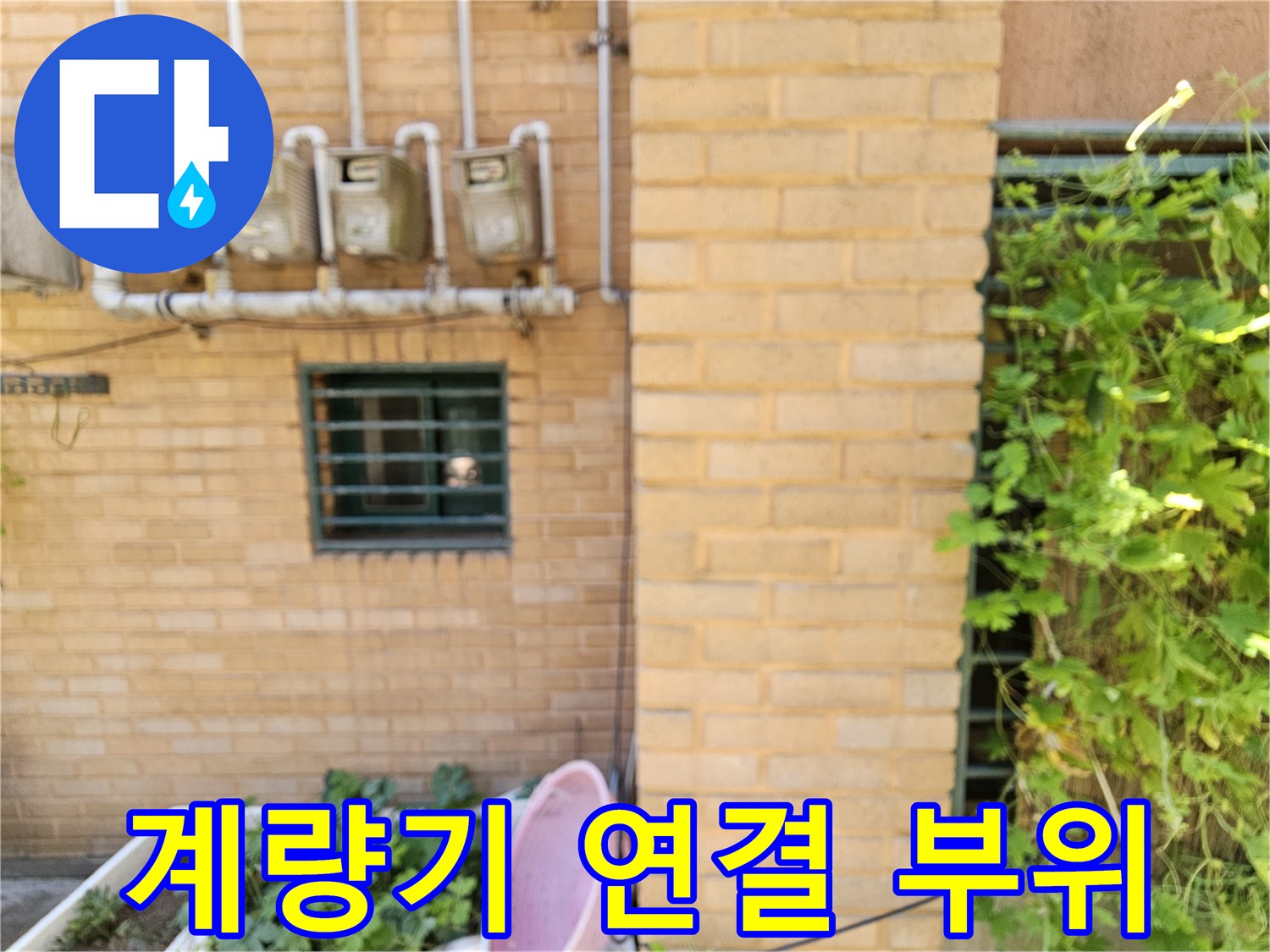 벽돌 벽면의 수도 계량기와 수직으로 뻗어있는 배관 구조물