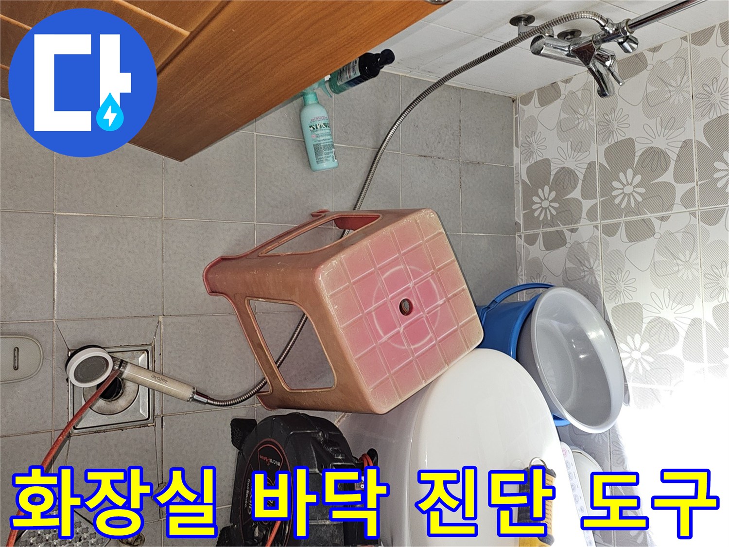 욕실 배수구 근처에 놓인 누수 탐지용 압력 게이지와 드릴