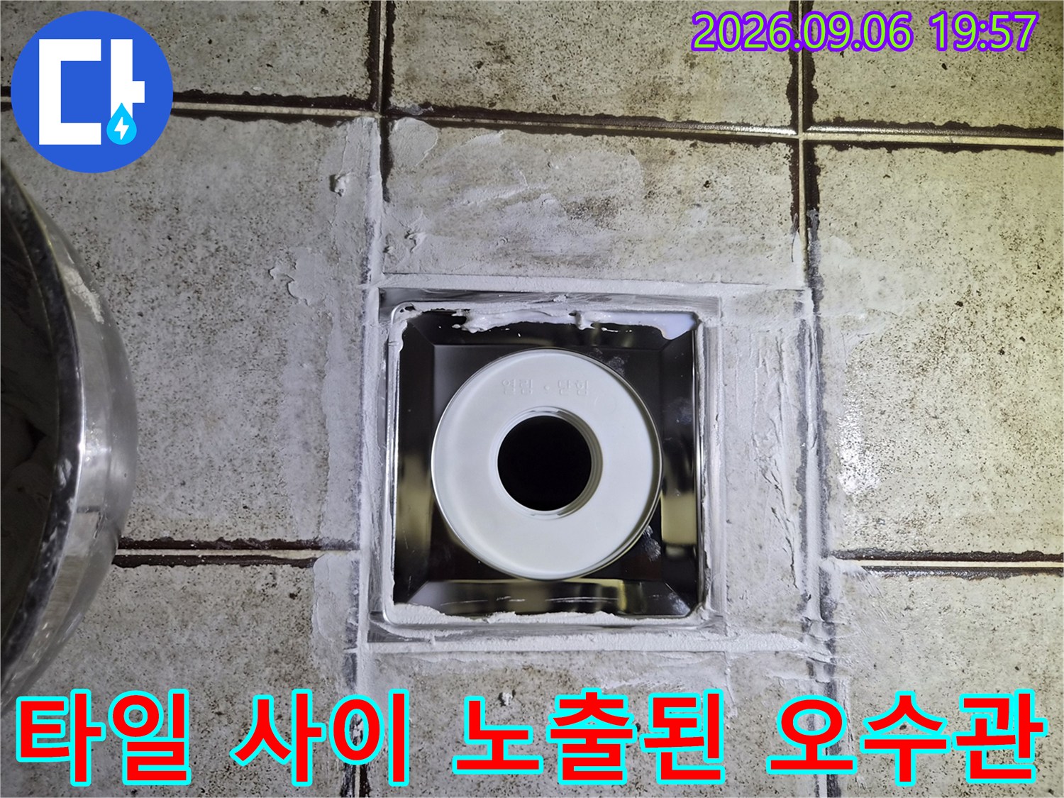 욕실 타일 틈새를 통해 보이는 하얀색 배관과 주변 마감재 상태