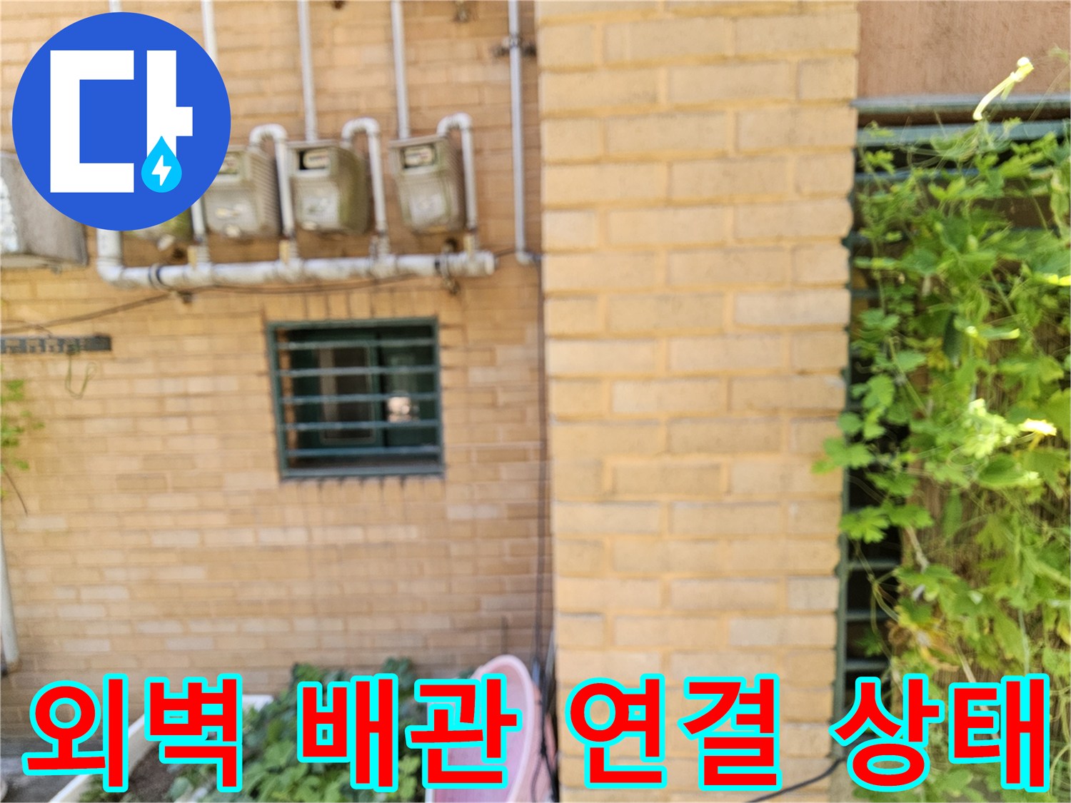 외부 벽면에 고정된 수도 계량기와 연결 배관의 모습입니다.