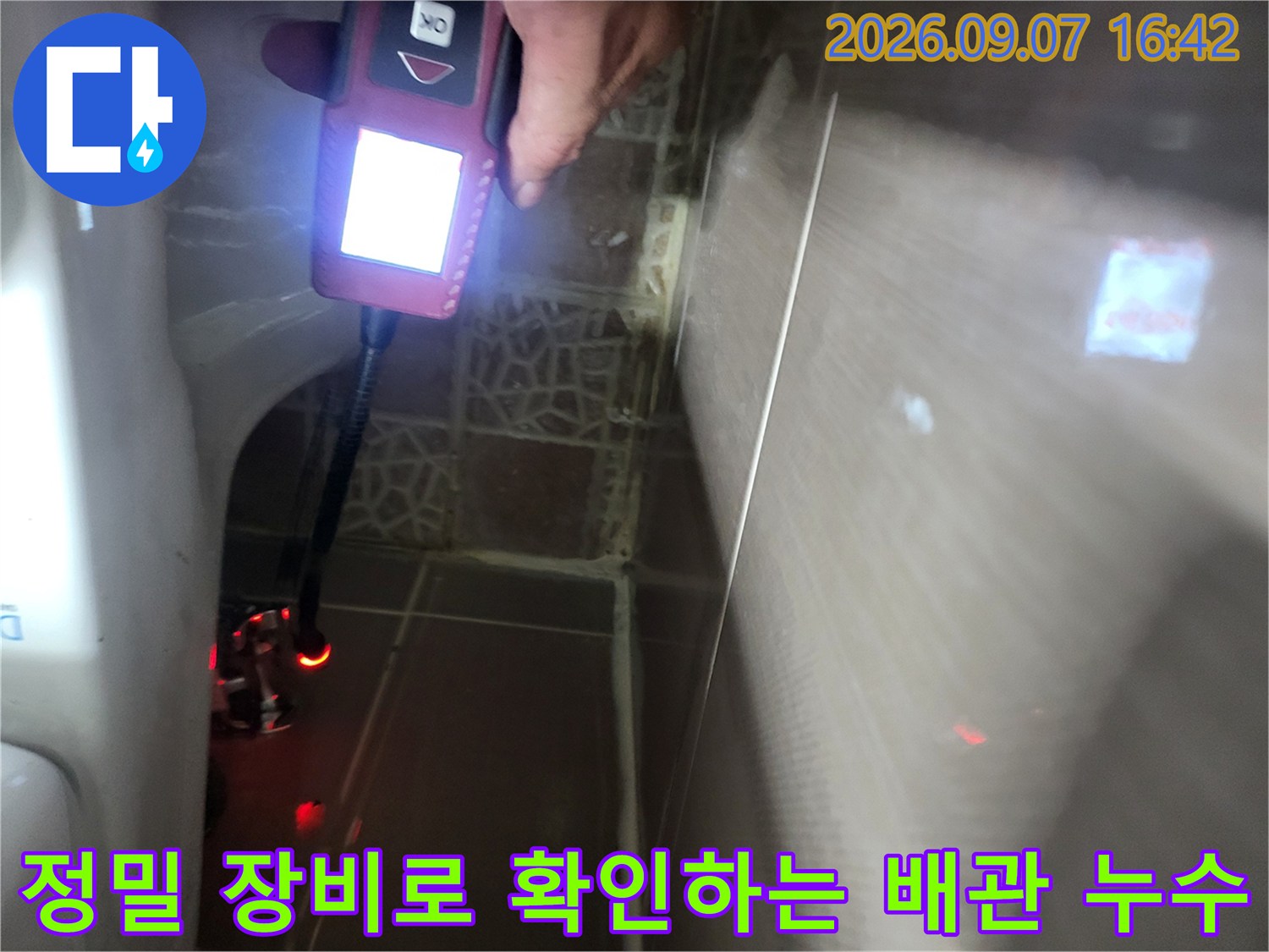 휴대용 가스 탐지기를 사용하여 화장실 벽면 틈새를 조사하고 있습니다.