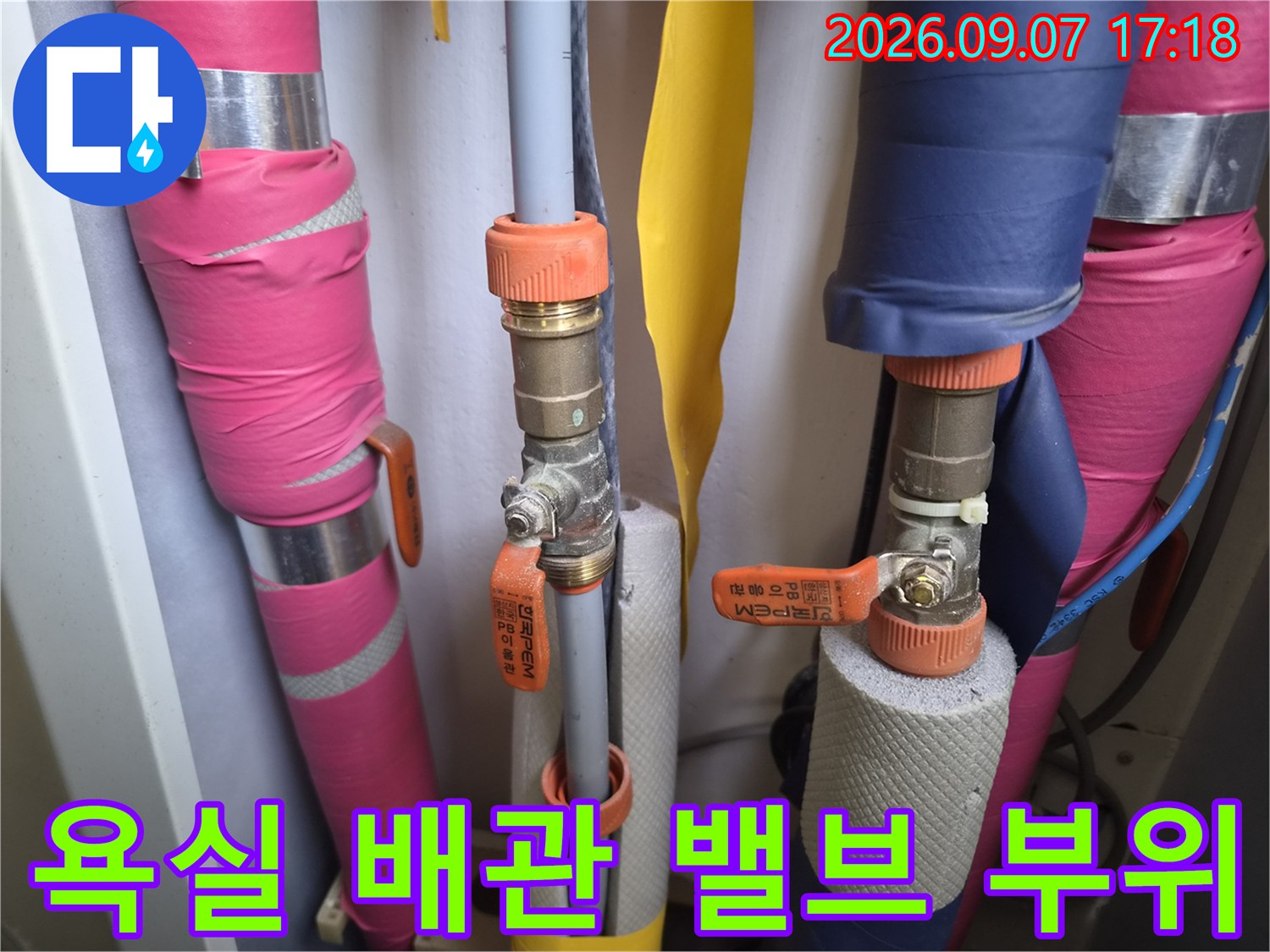 다양한 색상의 보온재가 씌워진-배관과 금속 밸브의 근접 사진입니다.