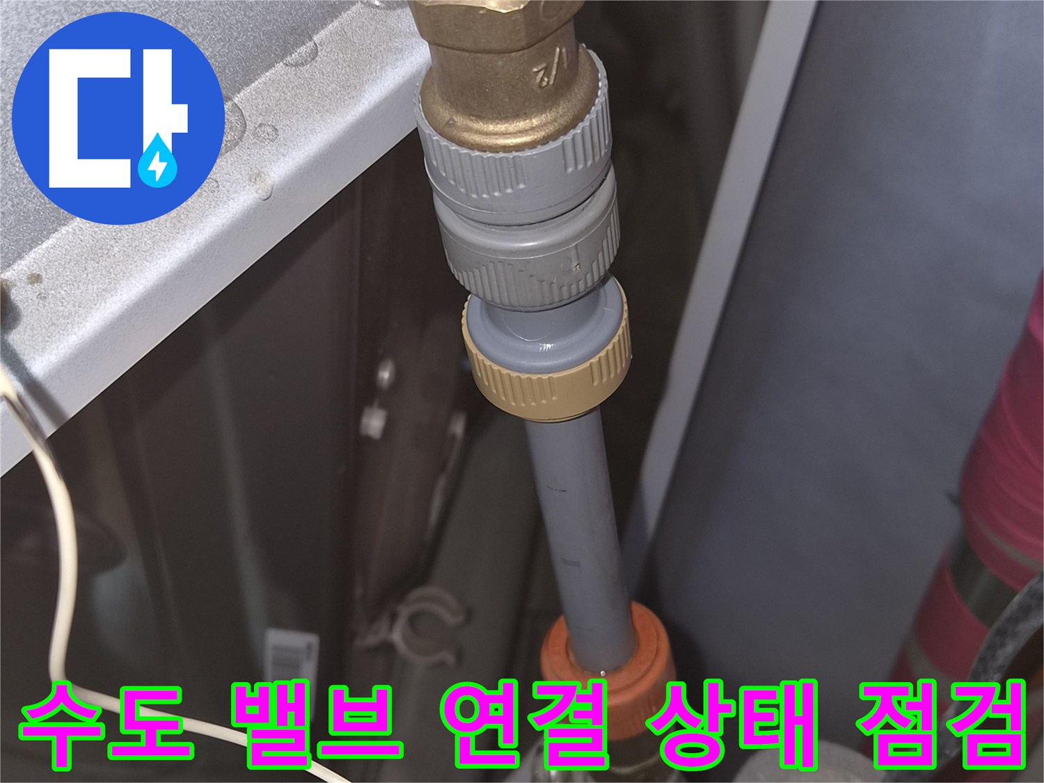 배관의 금속 부품과 회색 호스 연결 지점을 근접 촬영한 사진입니다.