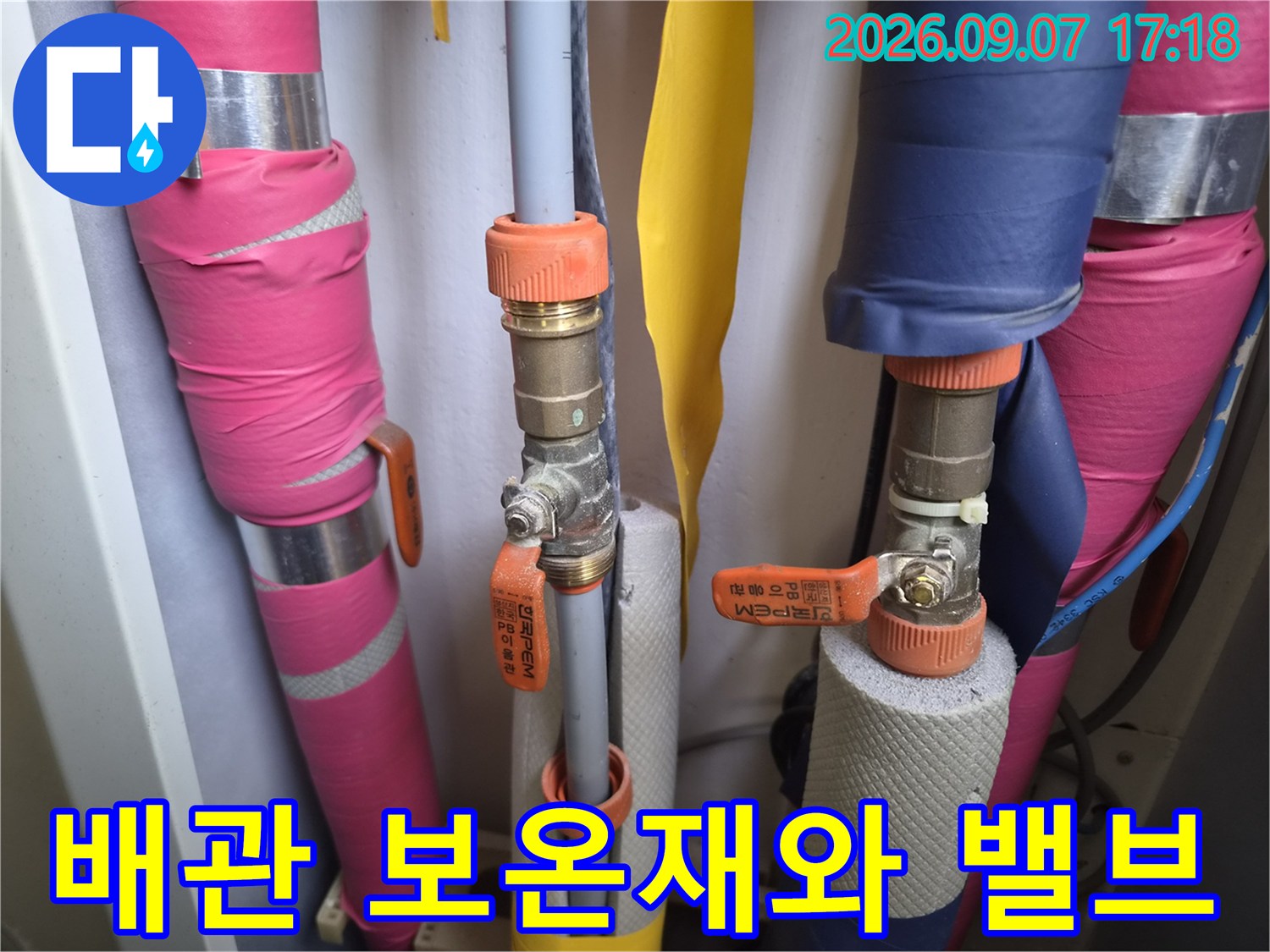 보온재로 감싸진 배관 사이의 밸브 연결 부위를 촬영한 사진입니다.