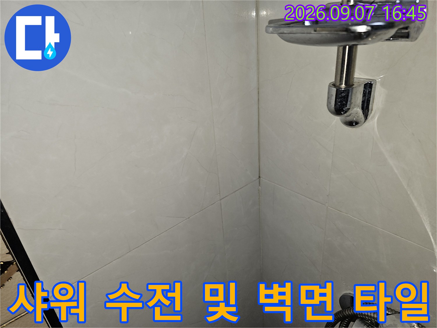 밝은 회색 무늬 타일과 금속 재질의 샤워기 수전 부위