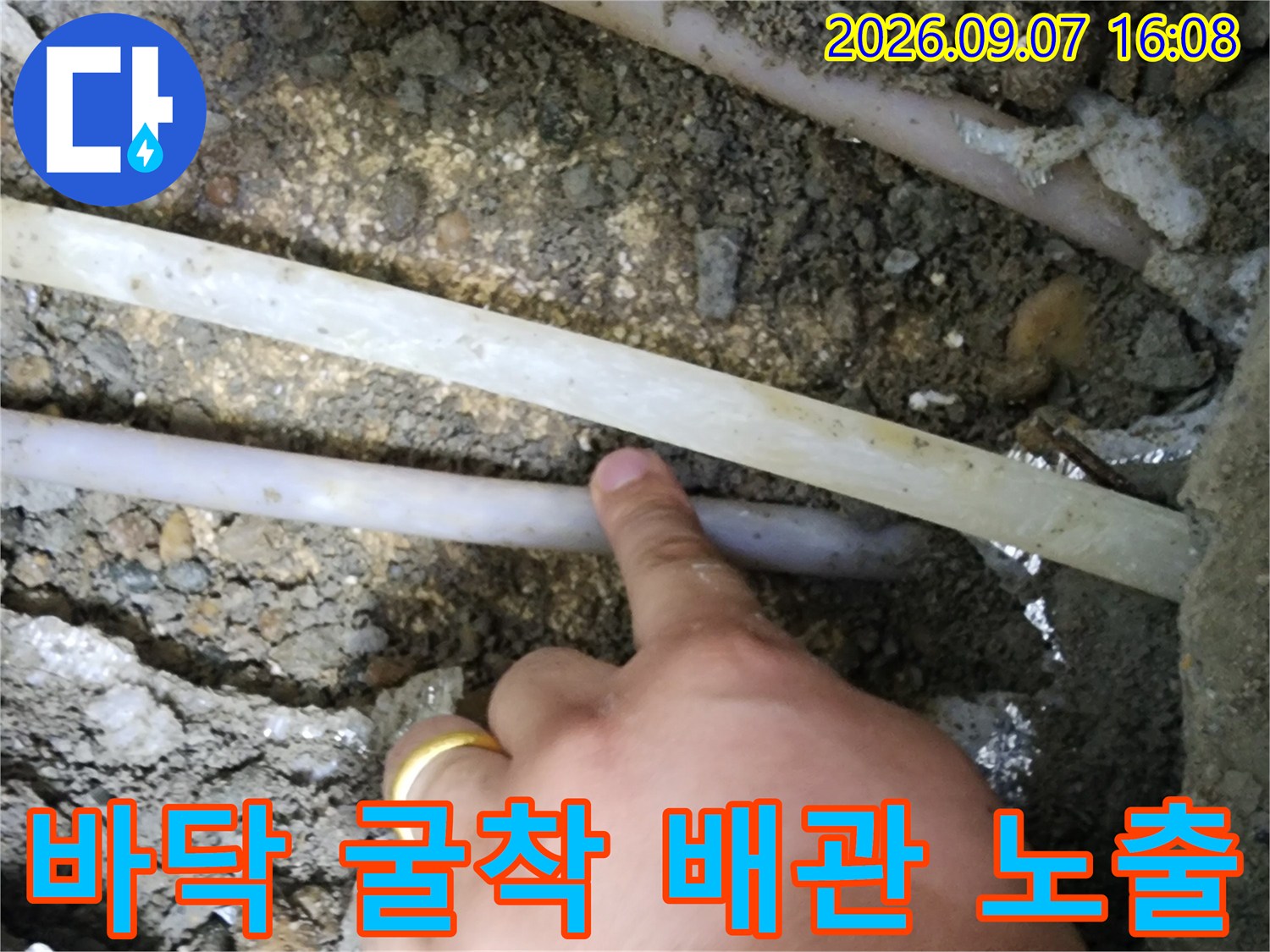 콘크리트 층을 파내어 드러난 수도 배관과 주변 토사의 모습입니다.