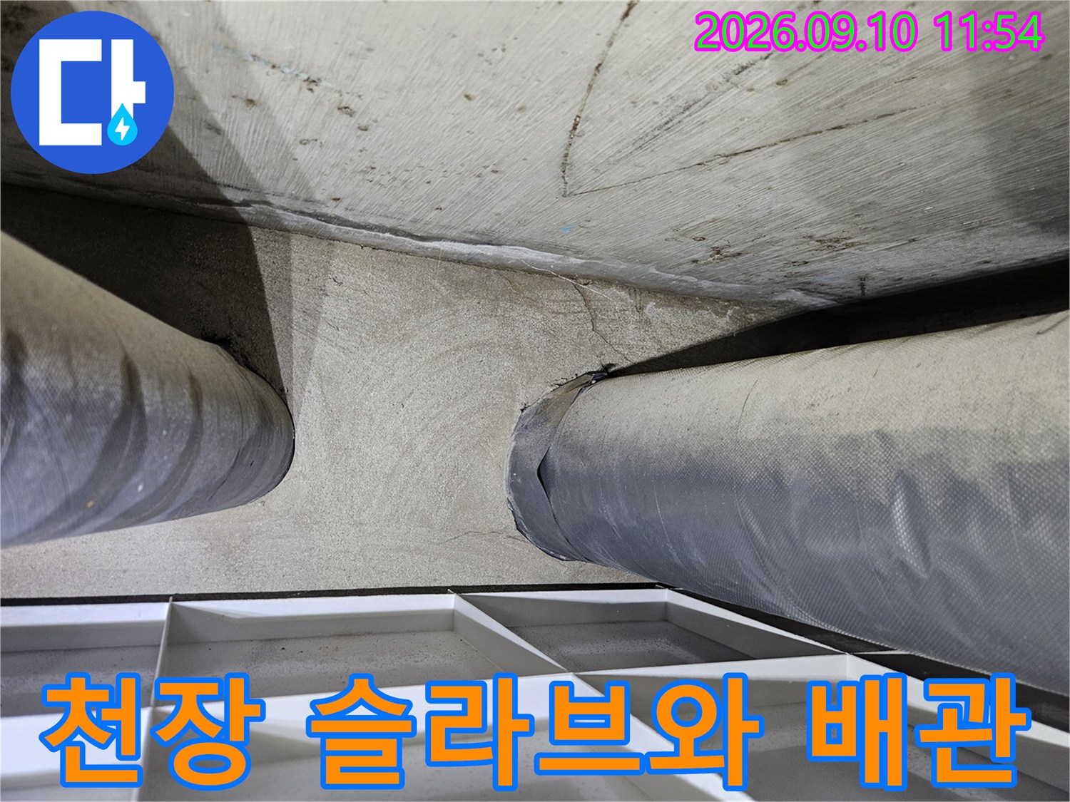 콘크리트 천장 구조물과 굵은 배관의 접합 부위 모습