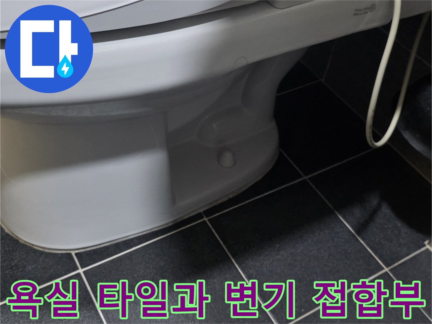 변기 하단과 어두운색 타일의 연결 부위 근접 사진