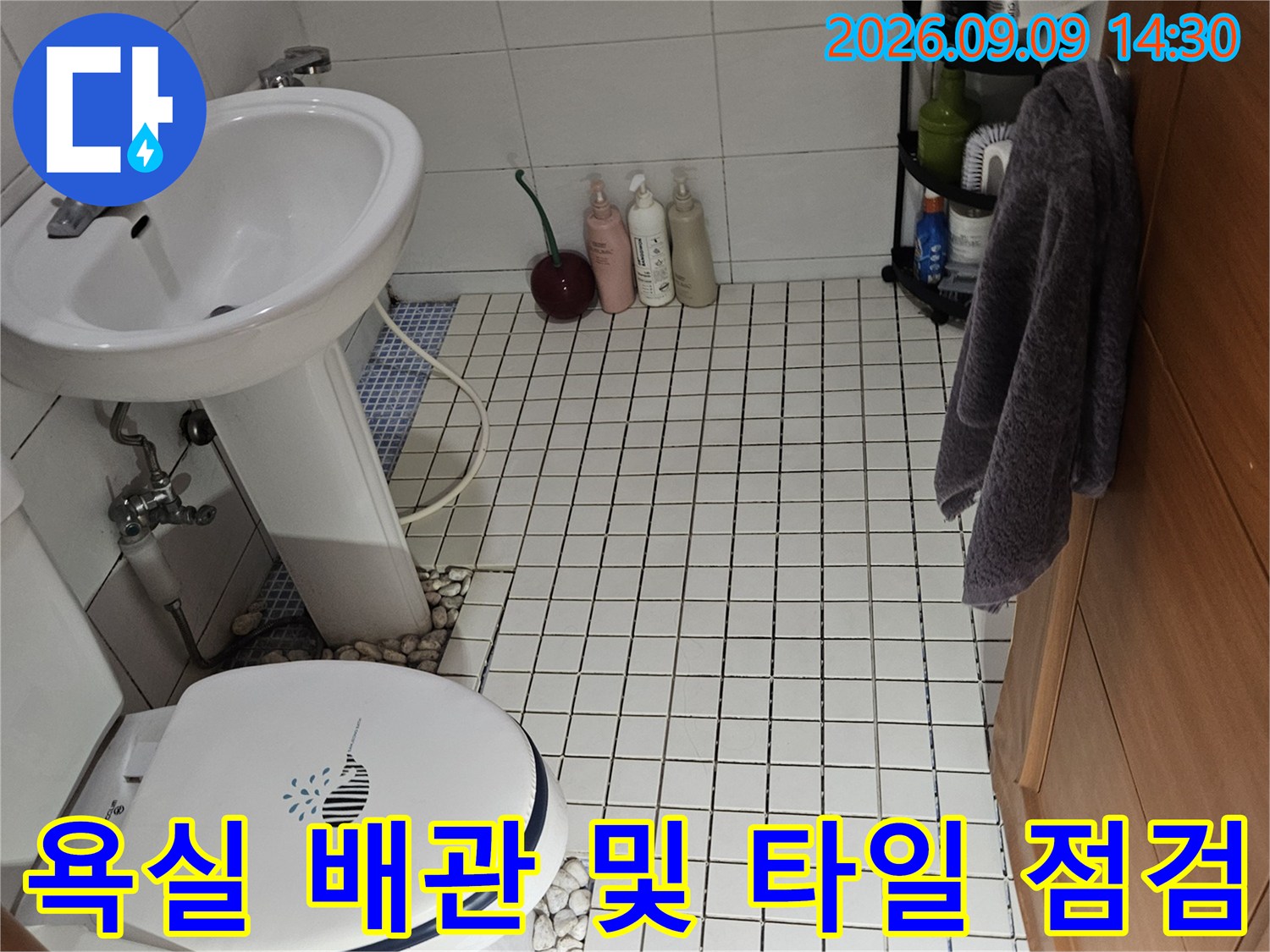 석촌동 욕실 현장의-세면대 하부 배관과 타일 벽면 상태를 보여줍니다.