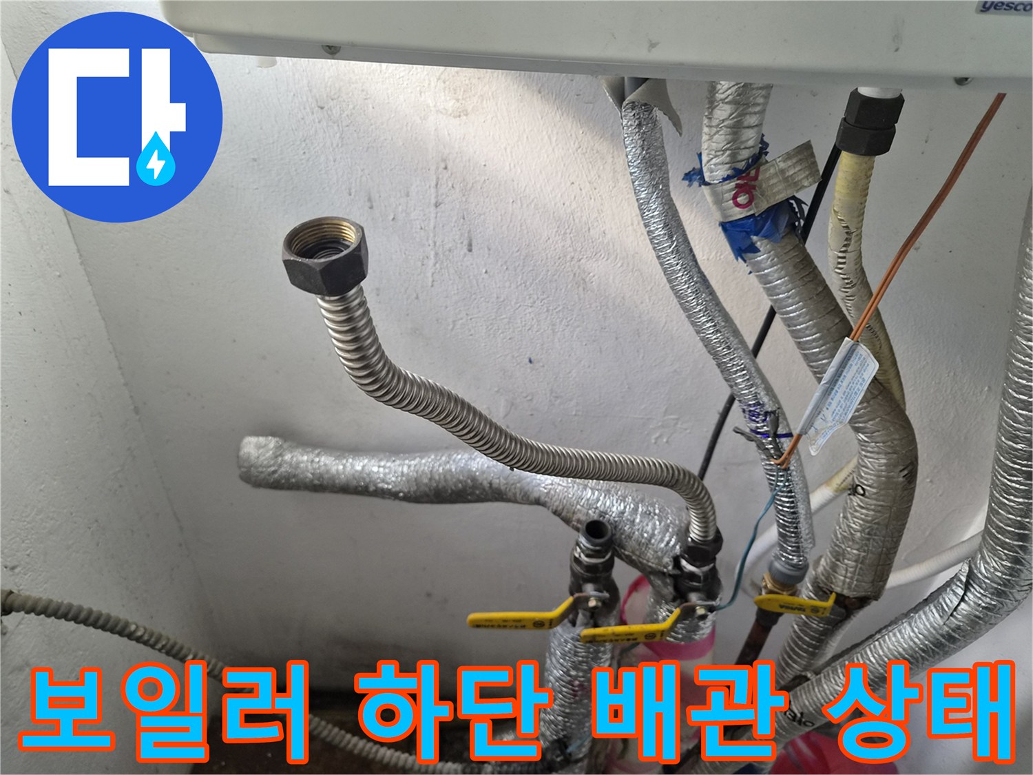 보일러 밑에 연결된 은색 주름관과 금속 부품 사진