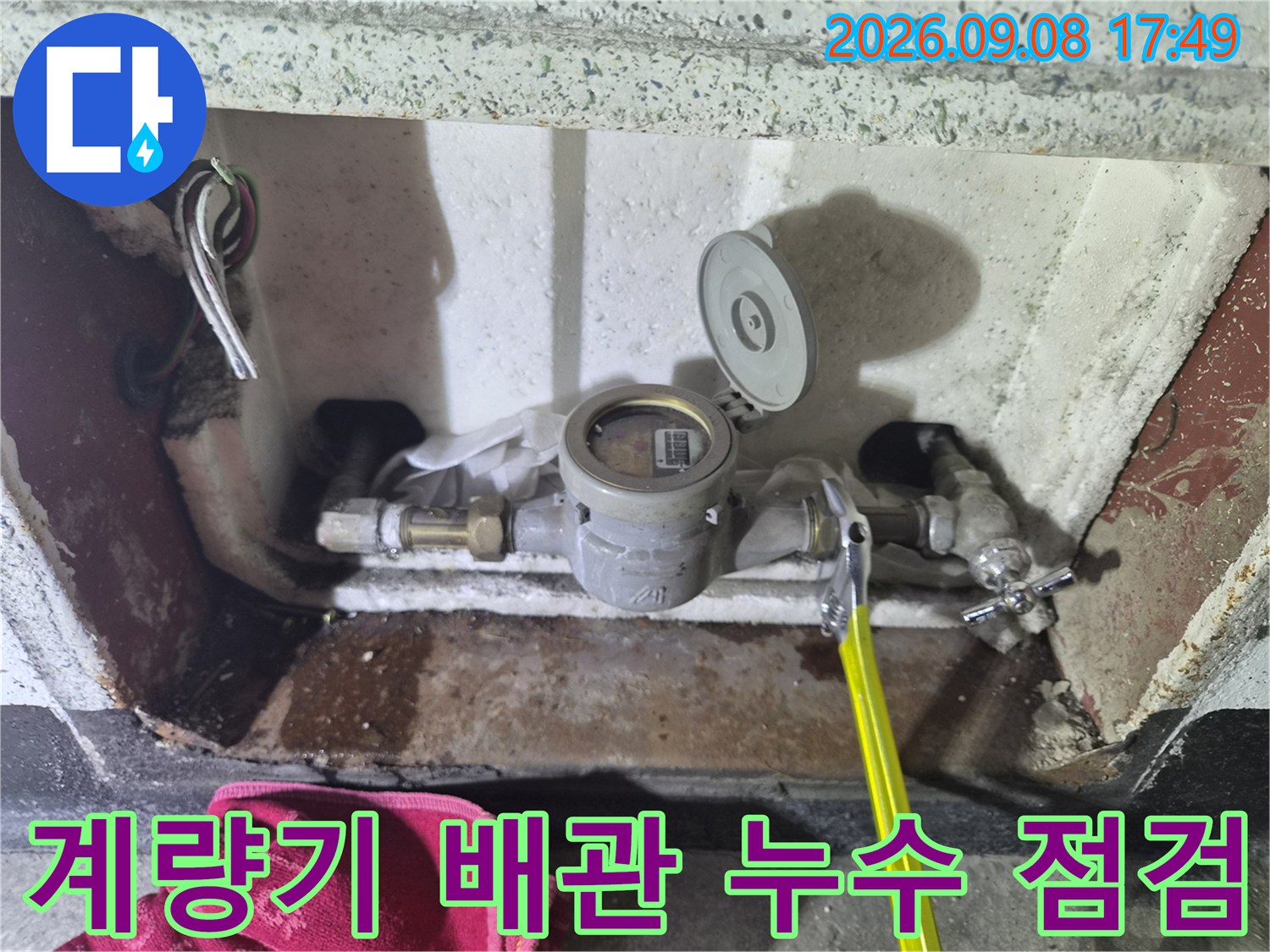 축축하게 젖은 수도 계량기 주변의 배관 연결 상태를 촬영한 사진입니다.