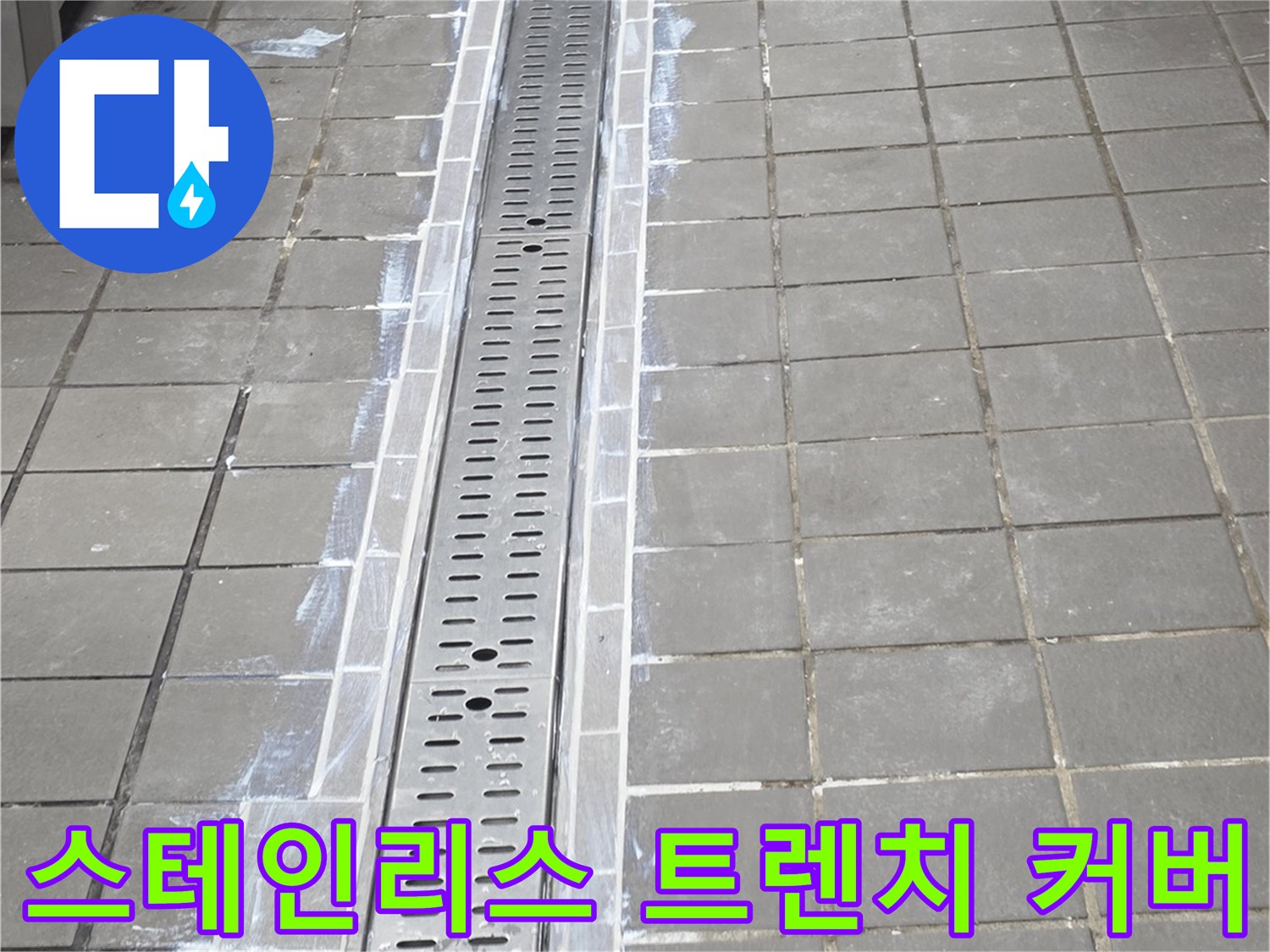 주방 바닥의 스테인리스-트렌치 배수구 덮개와 주변 타일 배열