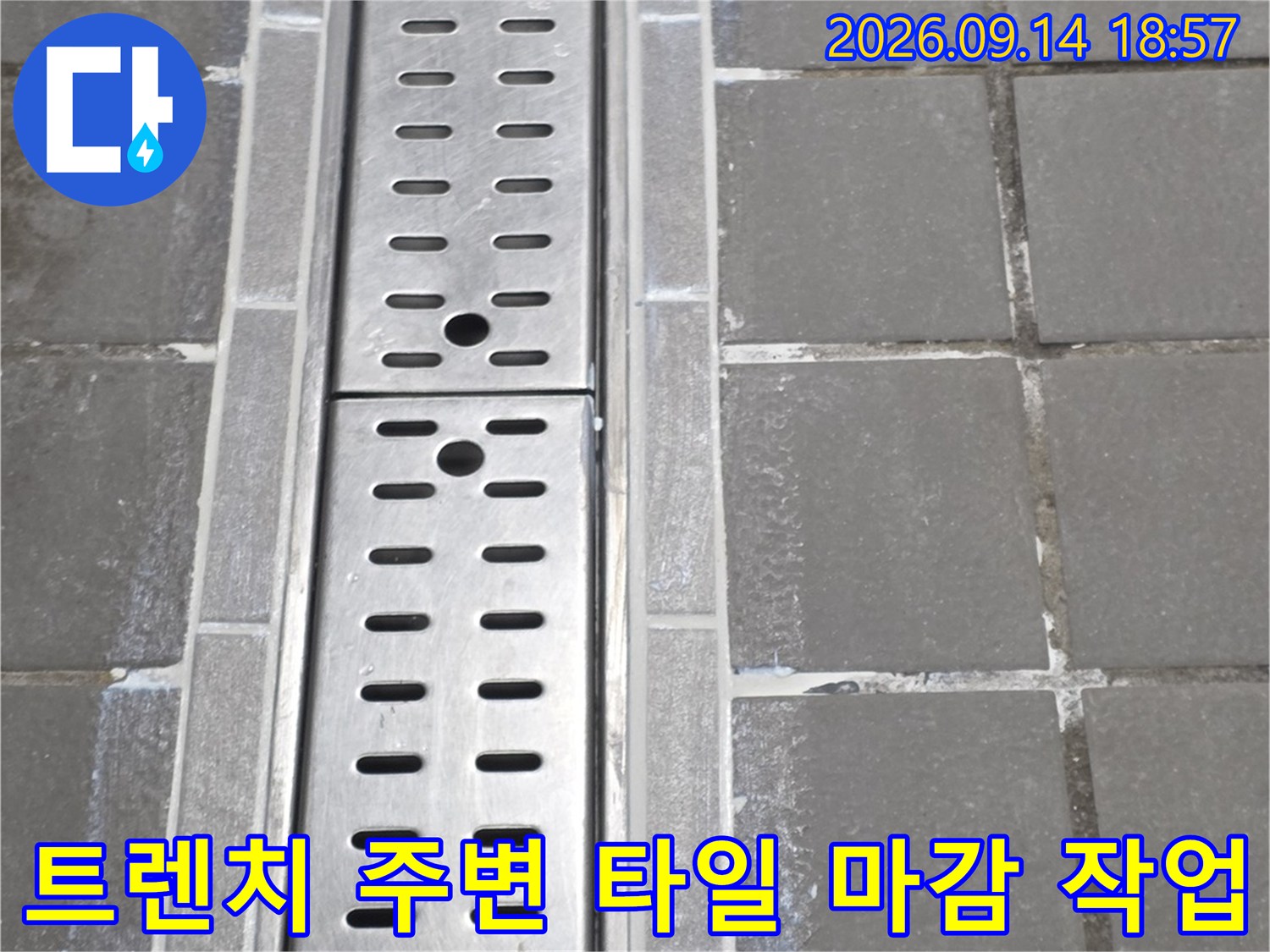 타일과 배수 트렌치 사이의 백시멘트 마감 처리가 완료된 현장 사진입니다.