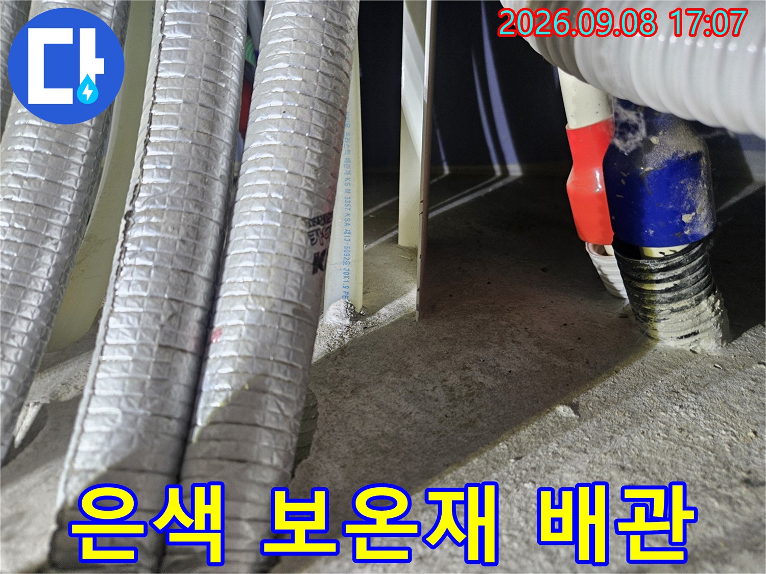 나란히 배열된 은색 보온재 씌워진 배관과 우측의 파란색 부속품