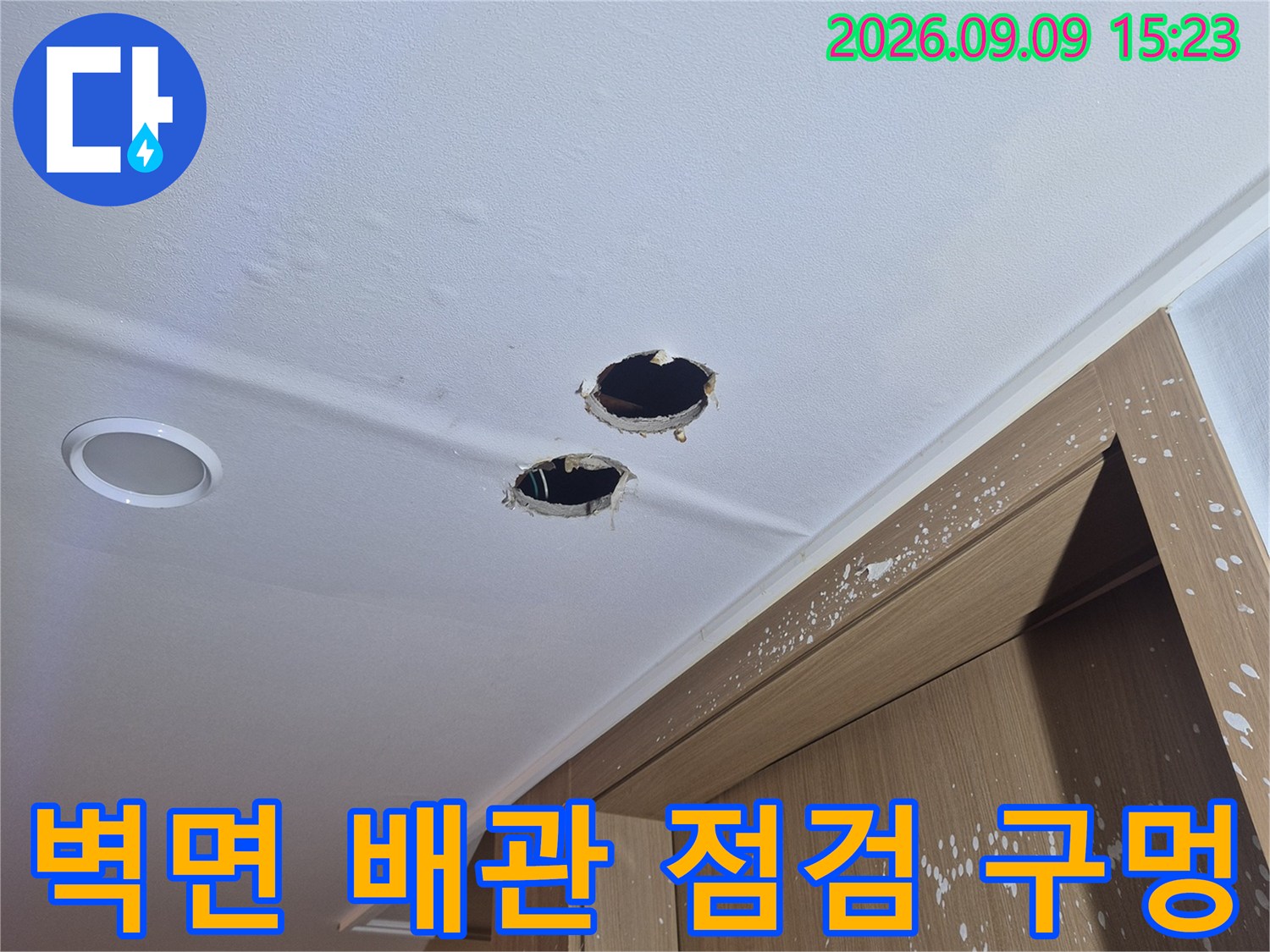 배관 누수 지점을 확인하기 위해 벽면에 만들어진 두 개의 작은 구멍과 타공 부위입니다.