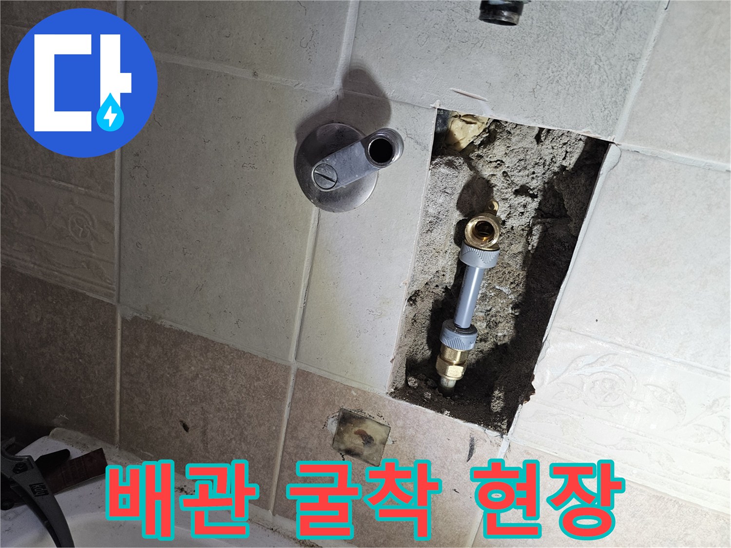욕실 타일 뒤편에 드러난 부식된 금속관과 밸브 하우징