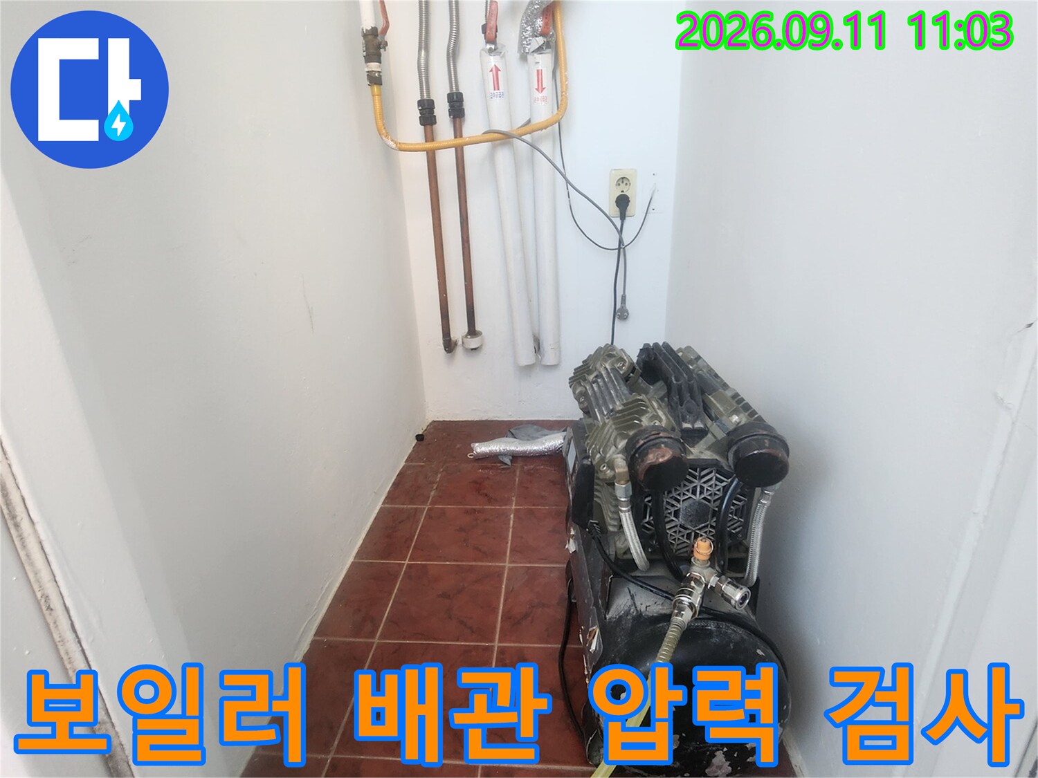 보일러실 바닥의 배관 연결 부위와 공압 측정 장비입니다.