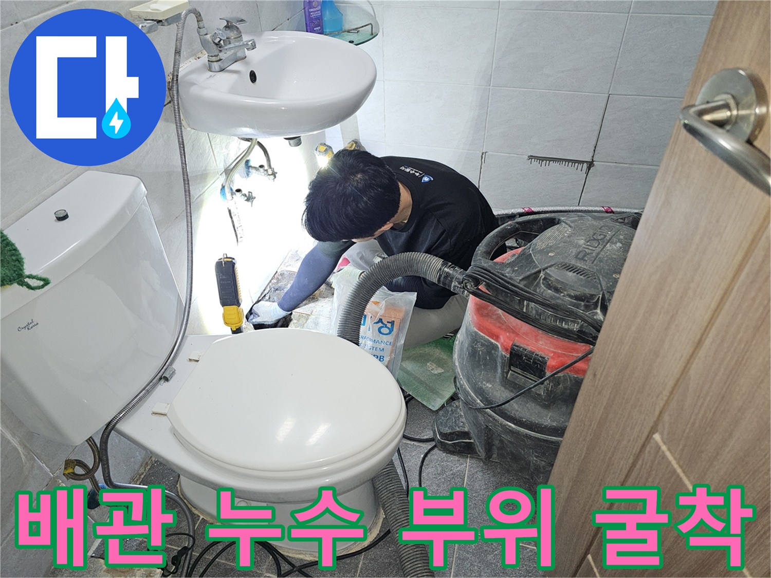 공구와 청소기를 사용하여 타일 아래 배관을 노출시키는 중입니다.