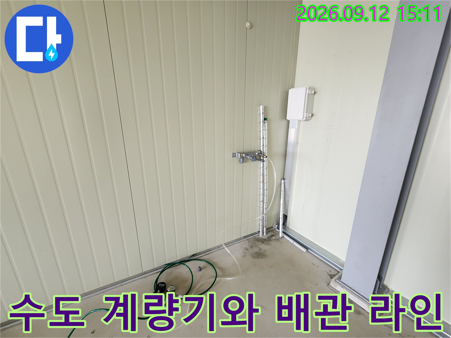 벽면에 설치된 수도 계량기와 연결되어 있는 금속 배관 모습입니다.