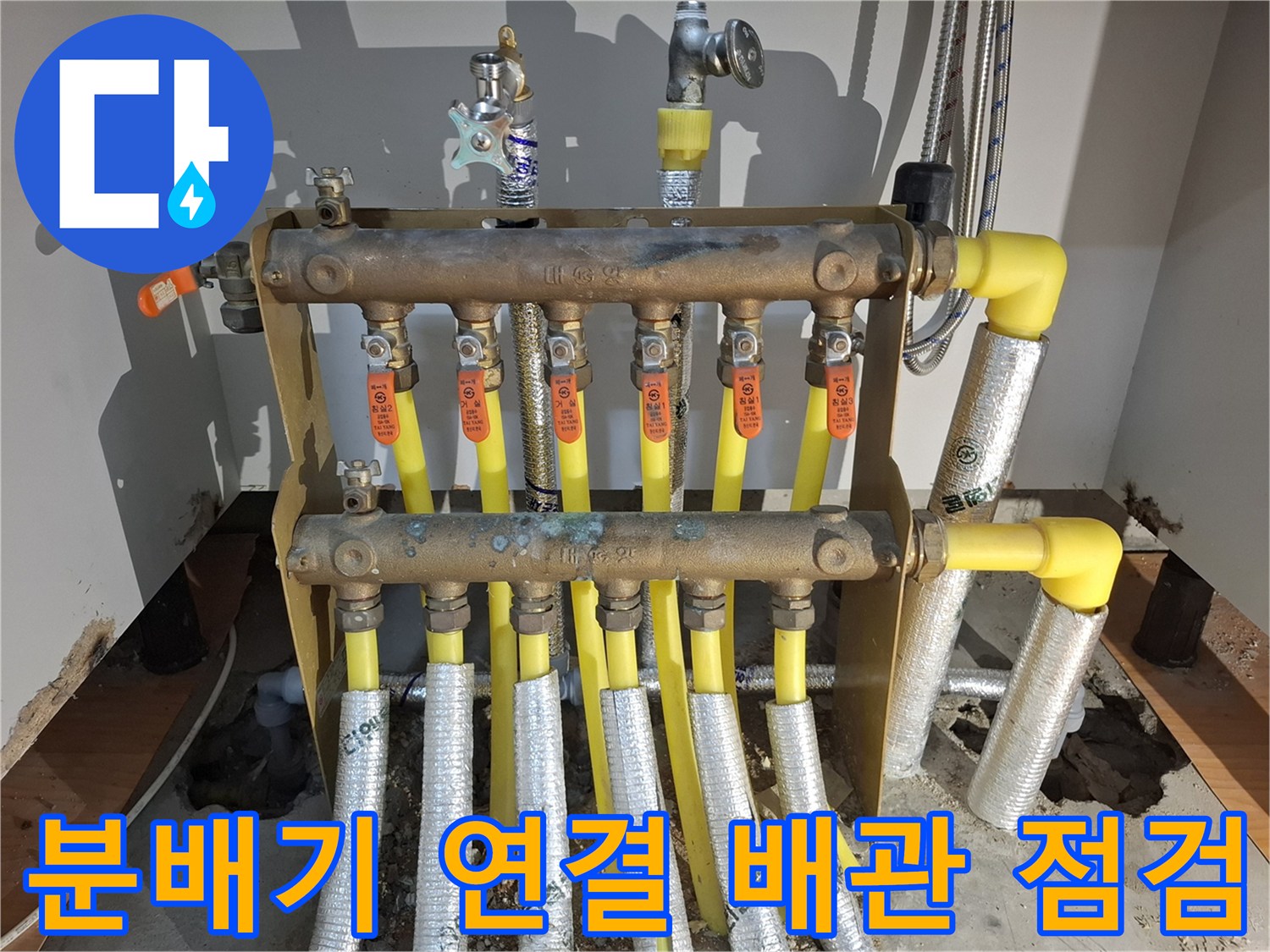 여러 갈래로 나뉘어 있는 노란색 난방 배관과 금속 분배기 본체 이미지