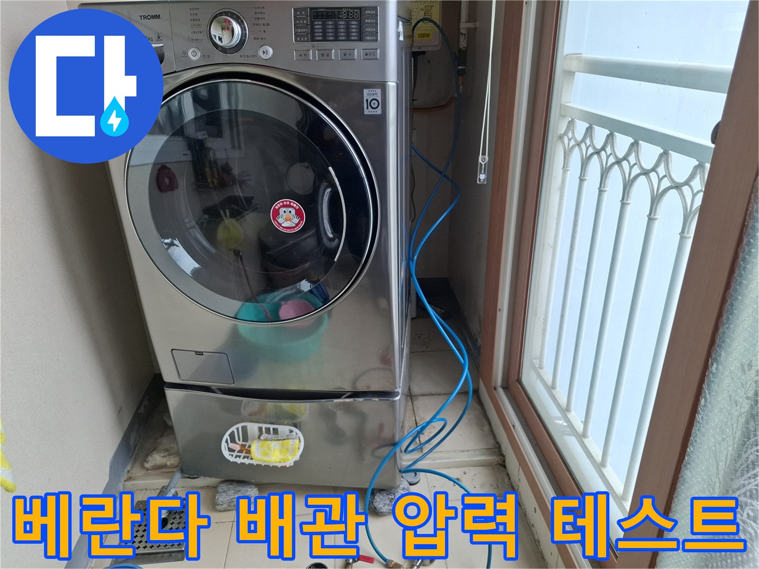 파란색 호스로 연결된 세탁실 바닥 배관의 기밀 테스트 장면