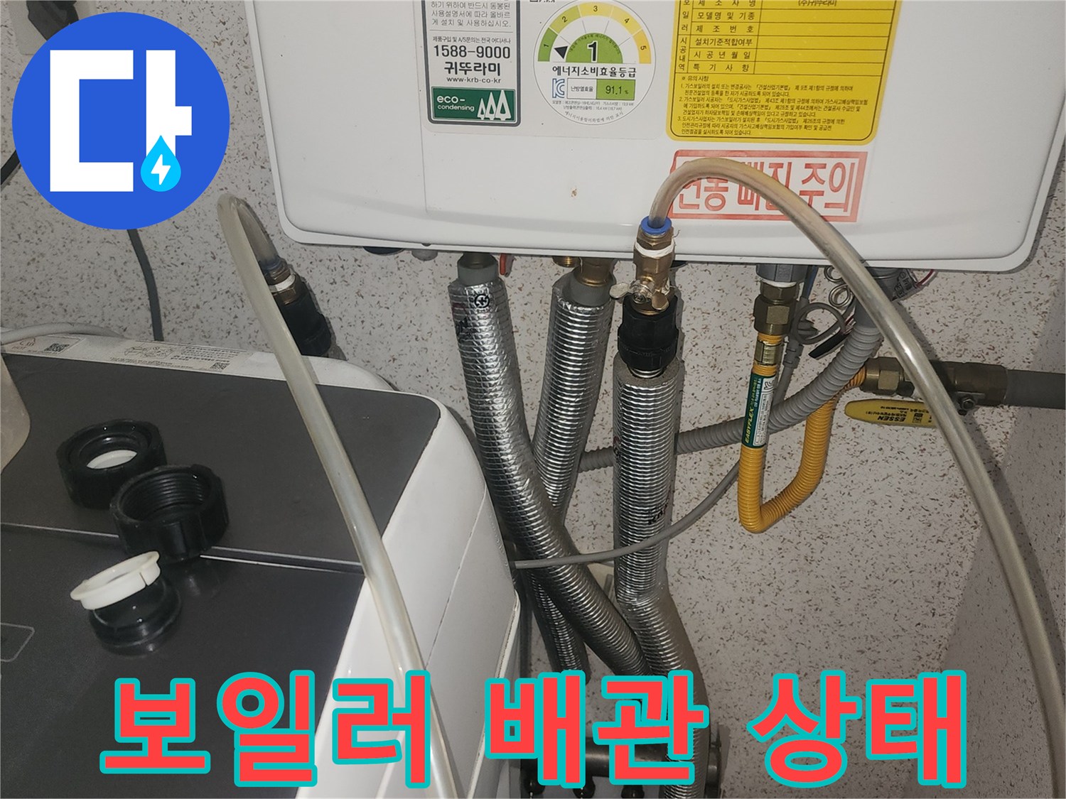 보일러실 하단에 연결된 금속 재질의 배관과 노란색 호스 모습