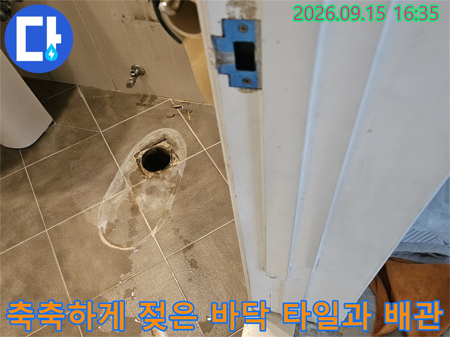배수구 주변의 젖은 타일 표면과 하얀 얼룩 현상