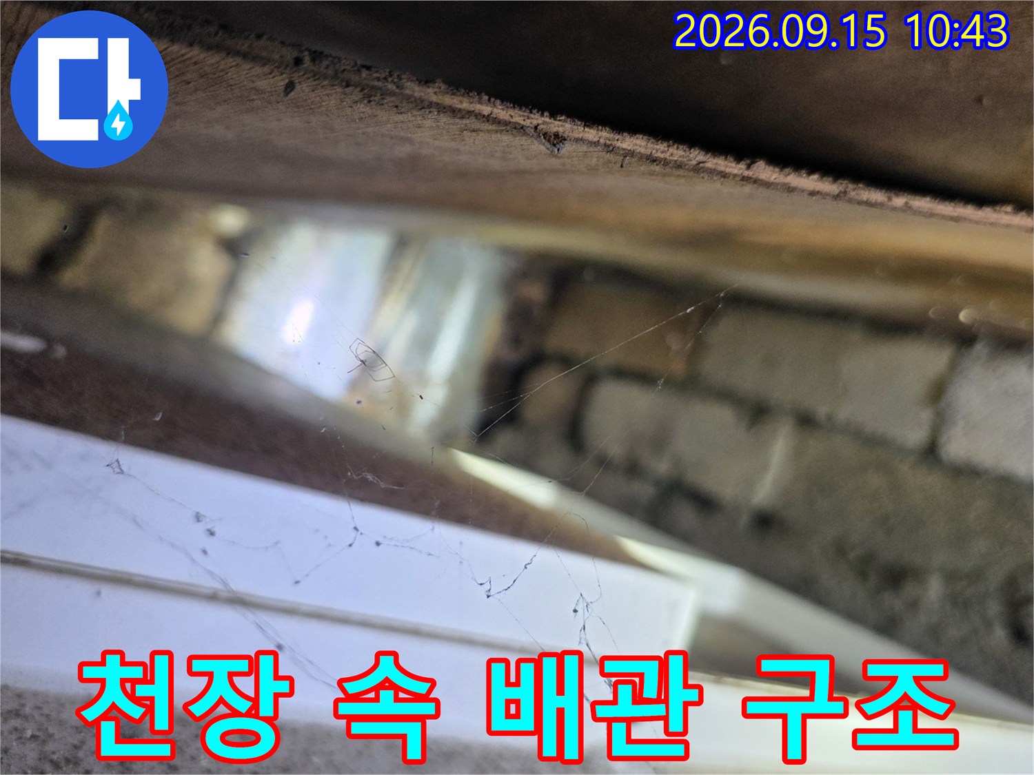 천장 내부의 벽돌 구조와 배관 주위 상태를 촬영한 사진입니다.