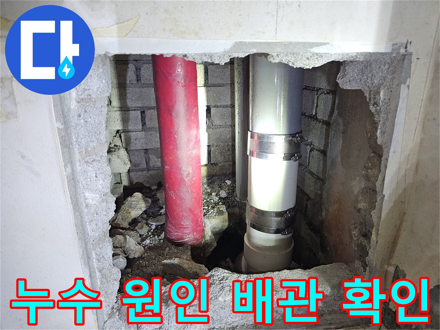 벽면을 뚫어 노출시킨 붉은색 및 회색 배관의 상태