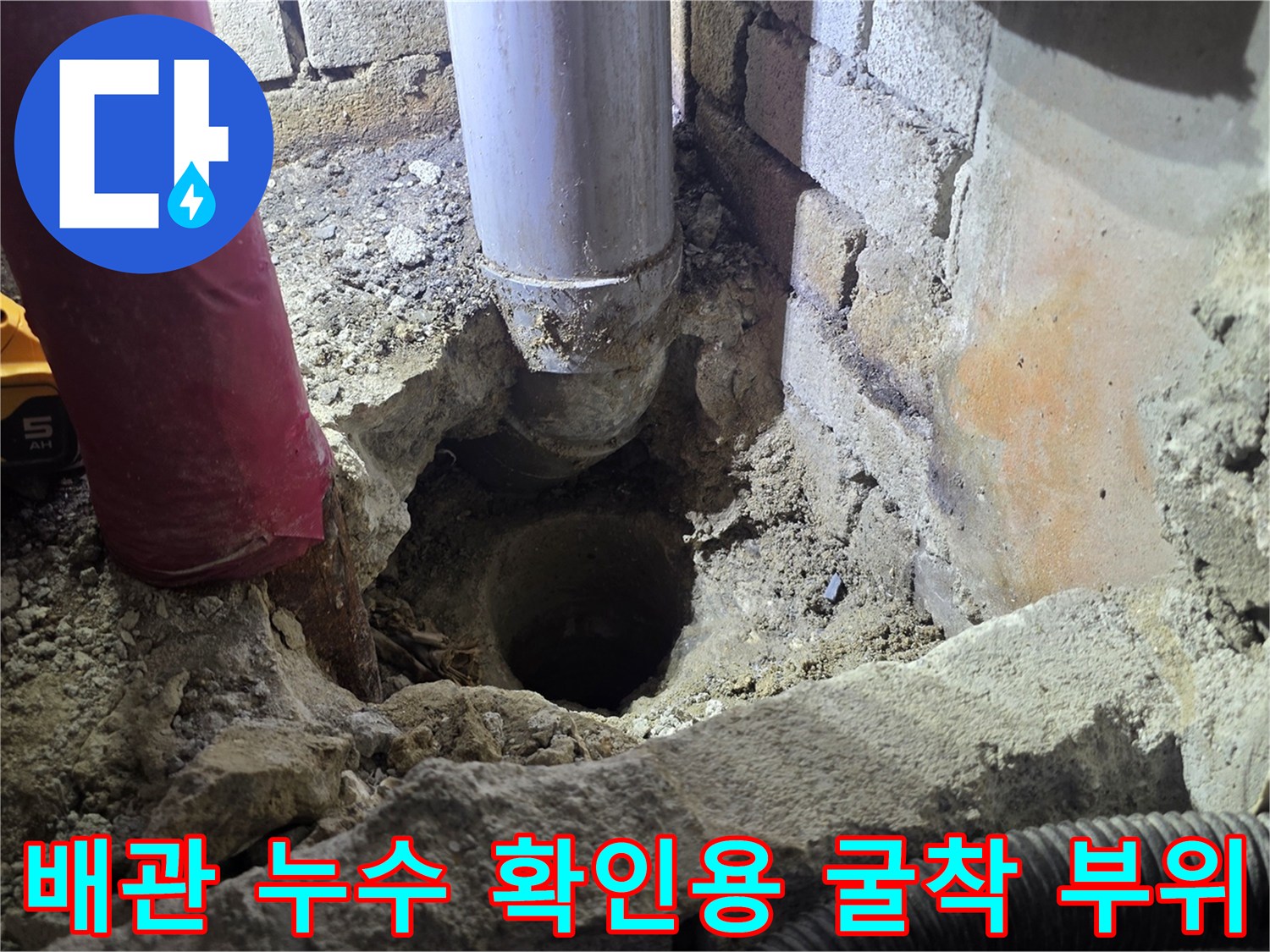 벽을 파내어 드러난 배관과 주변의 젖은 흙 및 장비 모습입니다.