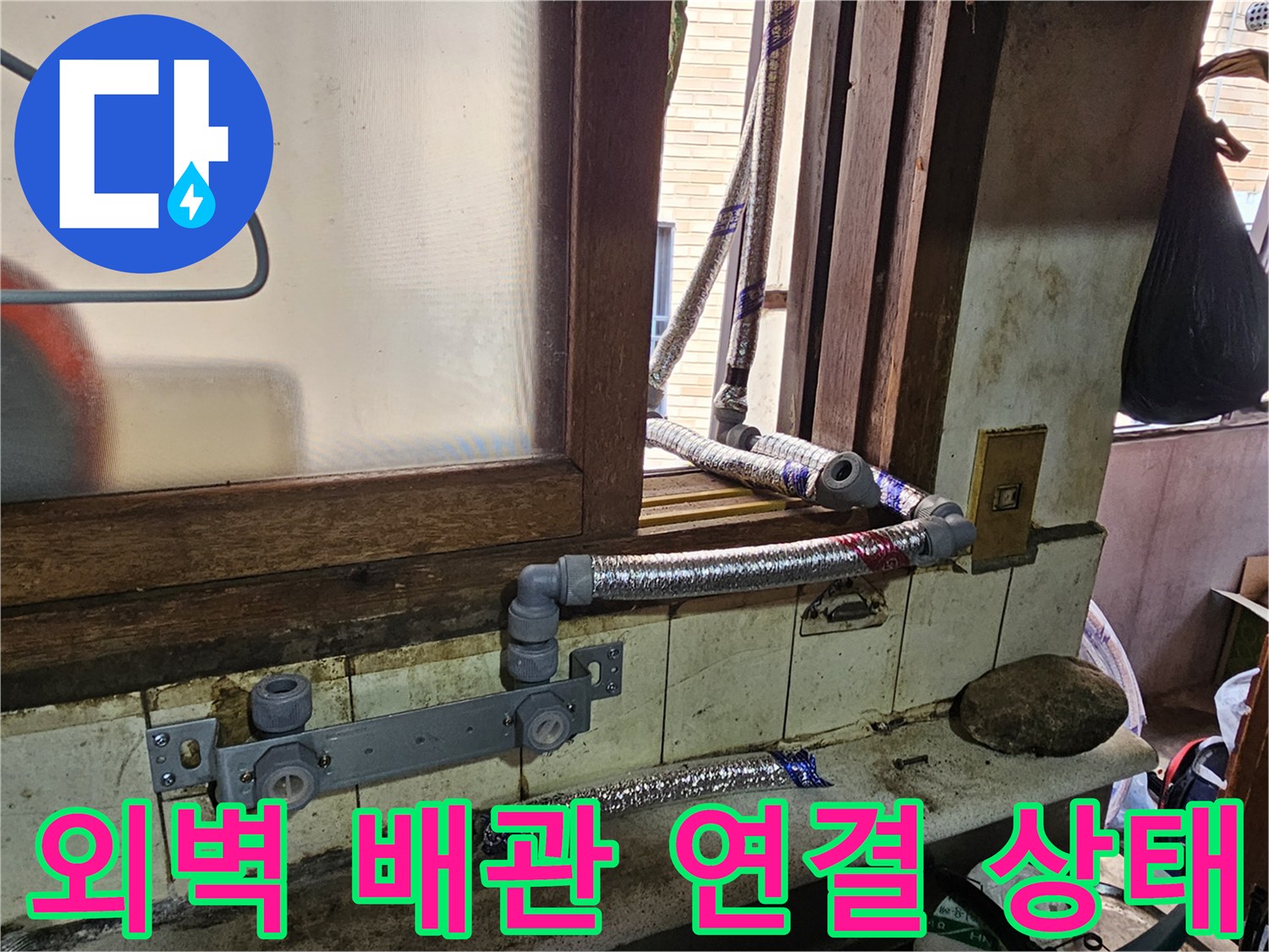 창문 아래 설치된 노후 배관과 은색 호스의 연결 부위입니다.